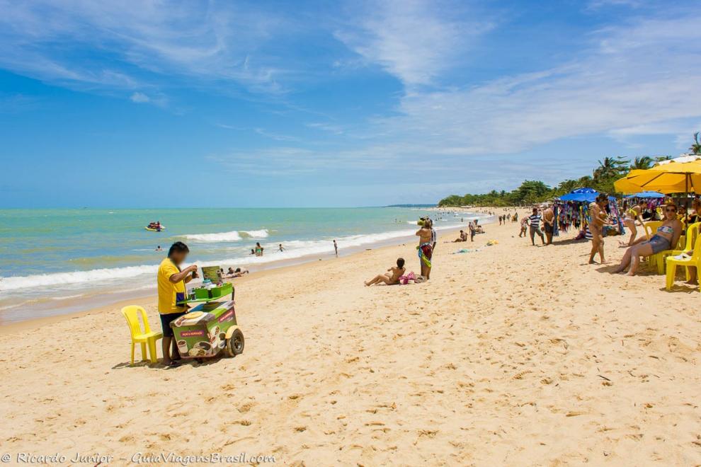 Imagem de um vendedor ambulante com carrinho nas areias da Praia de Taperapuan.